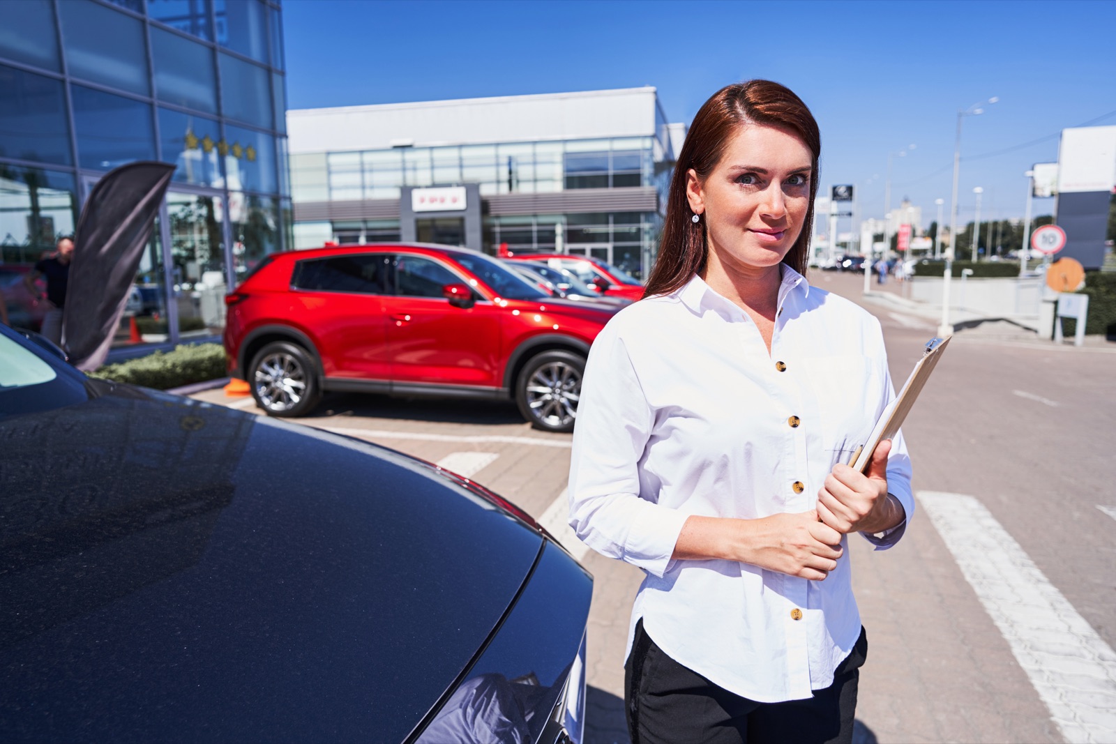 Trader on the forecourt with a clipboard next to new stock